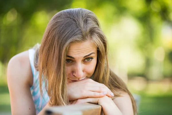 Porträtt av olycklig ung kvinna sitter i trädgården — Stockfoto