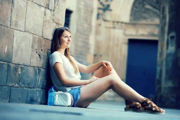 Молодая женщина сидит рядом со старой каменной стеной — стоковое фото
