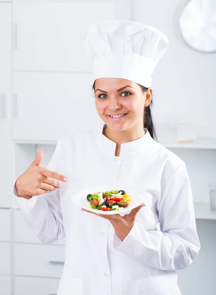 Femme cuisinier tenant assiette de salade — Photo