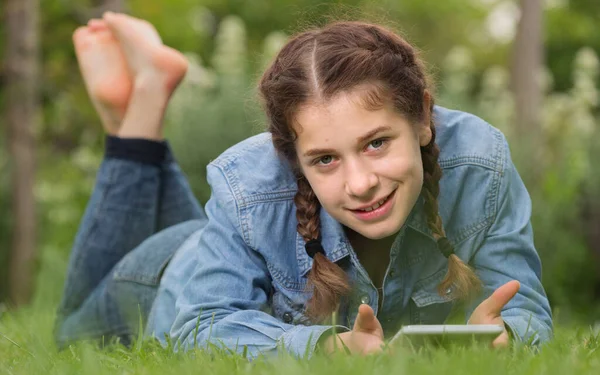 Smiling young female using digital tablet while lying in outdoors — Stock Photo, Image