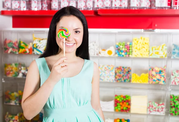 Sonriente chica chupando piruleta en la tienda —  Fotos de Stock