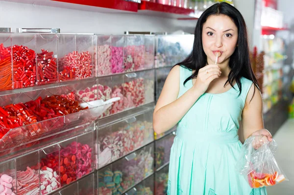 Chica bonita en la tienda de dulces recoge caramelos en la bolsa —  Fotos de Stock