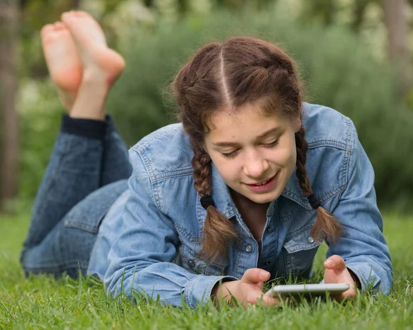 Χαμογελαστή νεαρή γυναίκα χρησιμοποιώντας ψηφιακή ταμπλέτα, ενώ βρίσκεται σε εξωτερικούς χώρους — Φωτογραφία Αρχείου