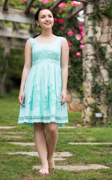 Portrait of young woman in dress near roses in a garden — Stock Photo, Image