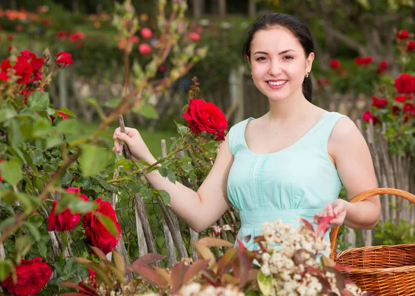 Porträt einer jungen Frau mit einem Korb in der Nähe von Rosen im Freien — Stockfoto