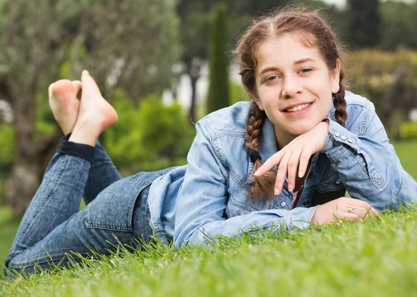 Portrét usmívající se mladé dívky ležící venku — Stock fotografie