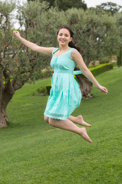 Joven morena mujer en vestido saltando al aire libre — Foto de Stock