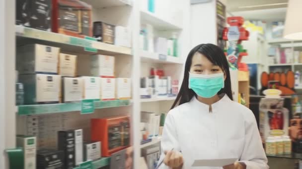 약국에서 얼굴을 보호하기 위해 마스크를 쓰고 있는 중국 여성 약사의 모습 — 비디오
