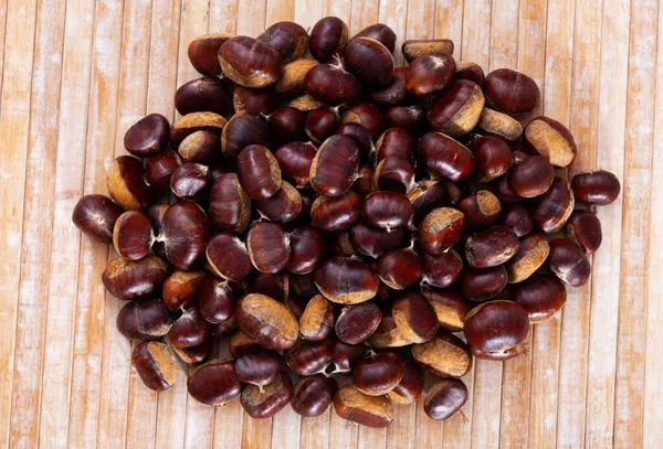 Pile of raw edible chestnuts on wooden surface — Stock Photo, Image