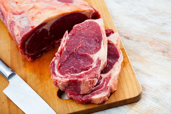 Rohes Rindfleisch mit Scheiben auf Holzoberfläche — Stockfoto