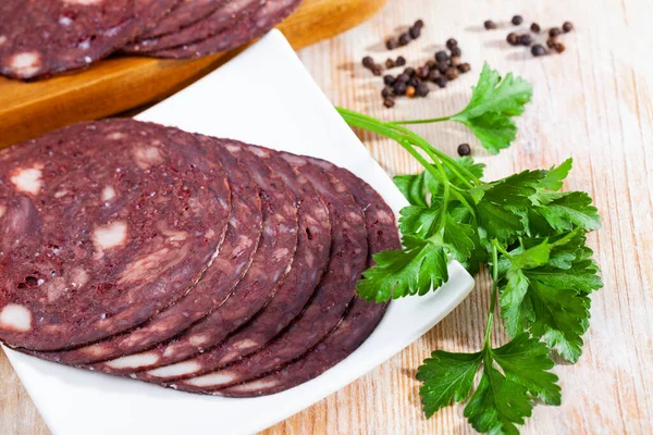 Close up of Spanish smoked blood sausage on white plate on wooden table — Stock Photo, Image