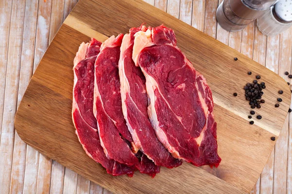 Skivade bitar av obearbetad filé av nötkött på skärbräda av trä — Stockfoto