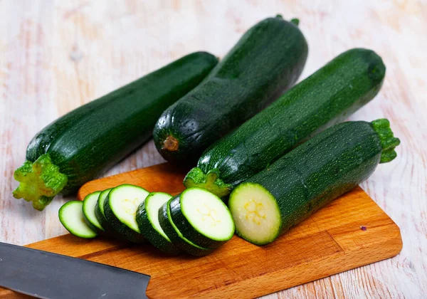 Closeup of fresh zucchini with chopped slices on wooden surface — Stock Photo, Image