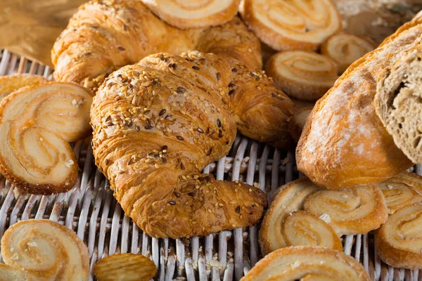 Croissant na macie rattanowej z innymi wyrobami piekarniczymi — Zdjęcie stockowe