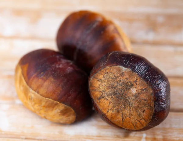 Pile of raw edible chestnuts on wooden surface — Stock Photo, Image