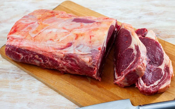 Frisches rohes Rindfleisch mit Messer auf hellem Holzgrund. — Stockfoto