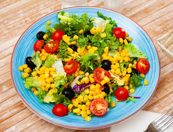 Plaat van heerlijke salade gemaakt van sla, tomaten, maïs, uien — Stockfoto