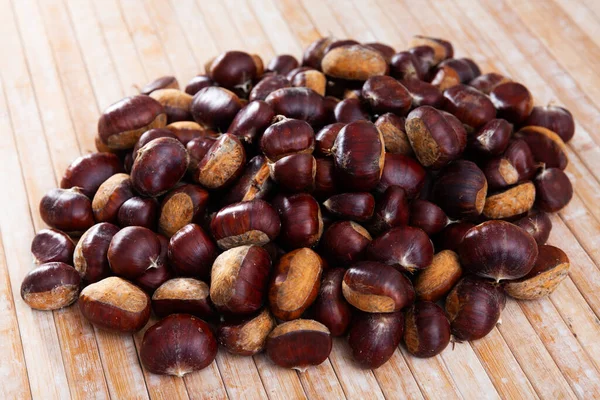 Unpeeled edible sweet chestnuts on wooden background — Stock Photo, Image