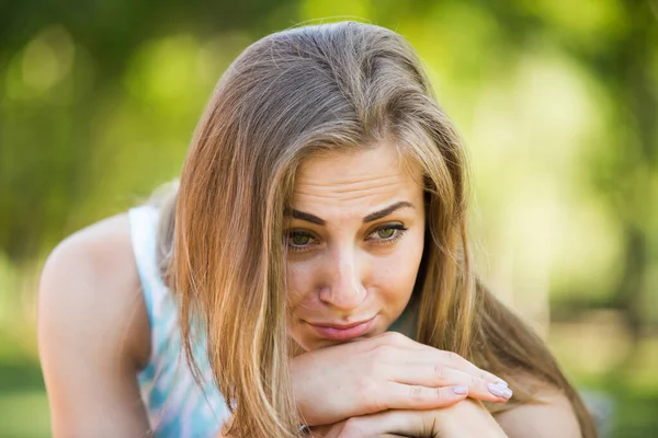 Porträt einer unglücklichen jungen Frau, die im Garten sitzt — Stockfoto