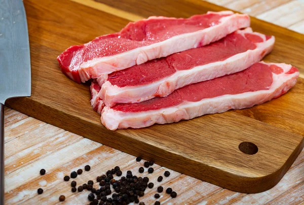 Surowa wołowina bez kości z przyprawami na drewnianym tle — Zdjęcie stockowe