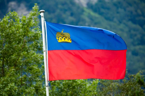 Bandeira de Liechtenstein acenando no fundo da montanha — Fotografia de Stock