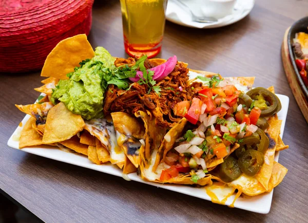 Kukoricaszirom nachos hússal, sajttal, zöldségekkel és guacamoléval — Stock Fotó