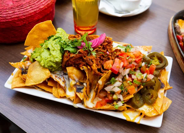 Grãos de milho nachos com carne, queijo, legumes e guacamole — Fotografia de Stock