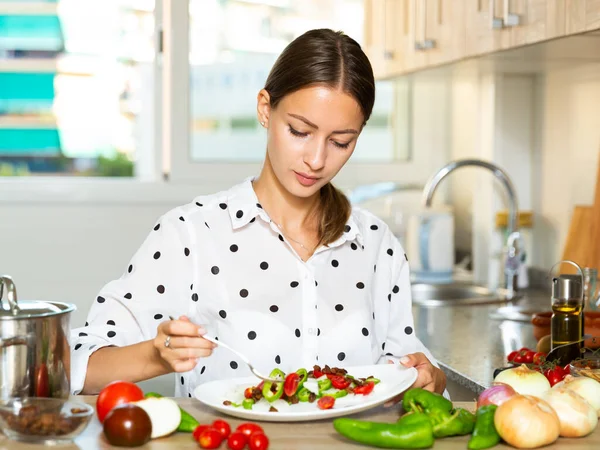 Girl tasting vegetable salad at kitchen — Stock Photo, Image