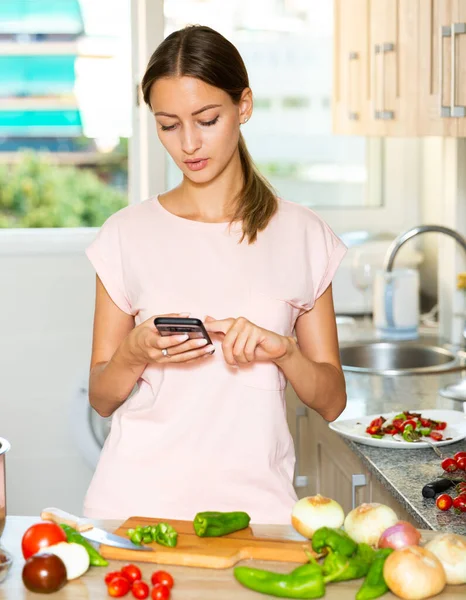 Mulher usando smartphone na cozinha — Fotografia de Stock