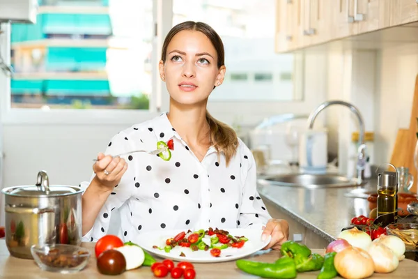 Mutfakta sebze salatası yiyen bir kız. — Stok fotoğraf