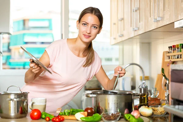 Meisje koken soep met behulp van laptop — Stockfoto