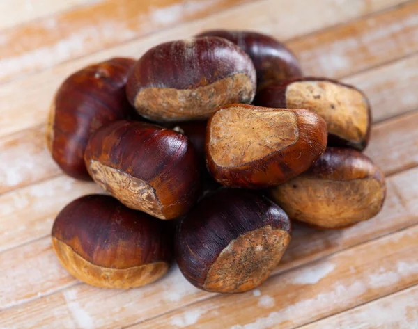 Castanhas doces comestíveis não descascadas em fundo de madeira — Fotografia de Stock