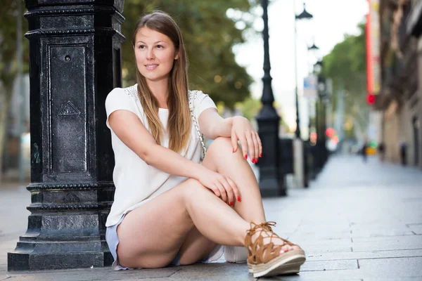 Junge Frau sitzt neben Laternenpfahl — Stockfoto