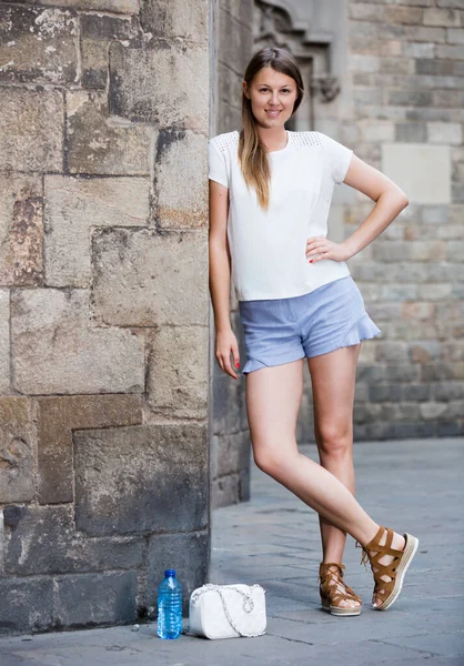 Giovane donna appoggiata contro il vecchio muro di pietra — Foto Stock