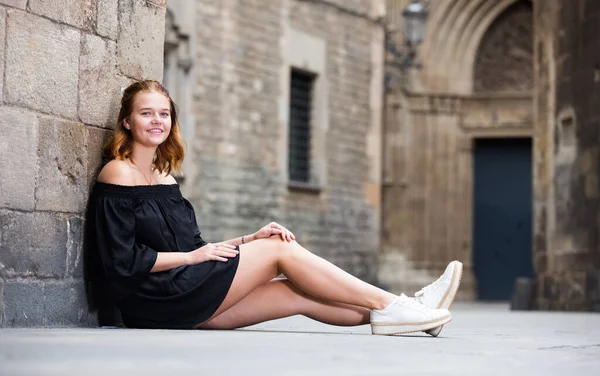 Chica joven positiva sentada en la calle — Foto de Stock