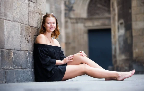 Chica positiva sentada descalza cerca de la pared de piedra — Foto de Stock