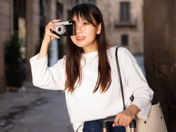 Giovane viaggiatore donna cinese passeggiando con i bagagli in giro per la città, facendo foto di attrazioni — Foto Stock