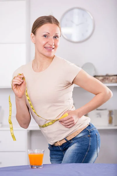 Mulher sorridente medindo cintura — Fotografia de Stock