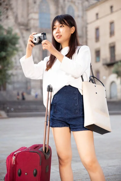Sorrindo menina segurando câmera nas mãos e fotografando na cidade — Fotografia de Stock