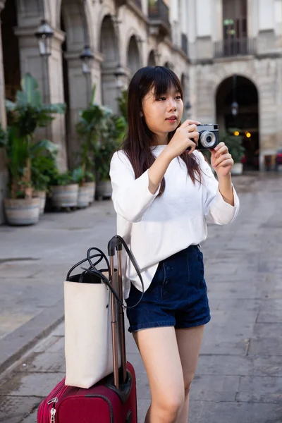 A fiatal kínai lány fényképeket készít a kamerájával, miközben a városon keresztül utazik. — Stock Fotó