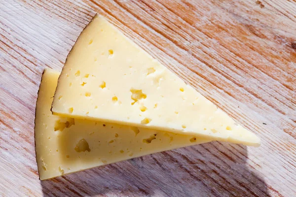 Tahta bir masada yarı sert bir peynir dilimi — Stok fotoğraf