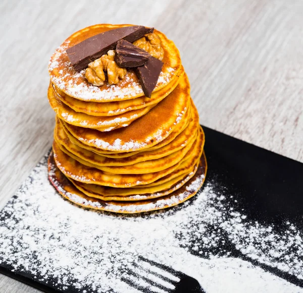 Pancakes served chocolate, walnut and powdered sugar at plate — Stock Photo, Image