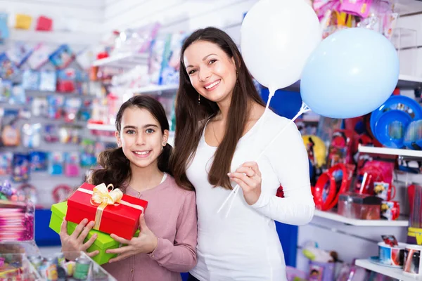 Portrait of mother and daughter holding gifts and balloons in store — Stock Photo, Image