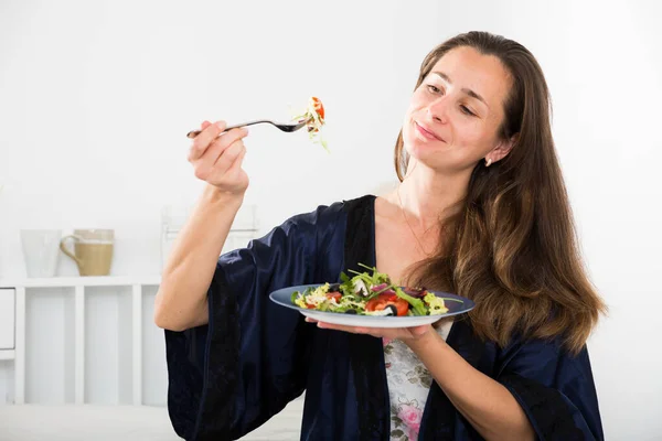 Joven bonita mujer comiendo ensalada de verduras de plato en la cama —  Fotos de Stock