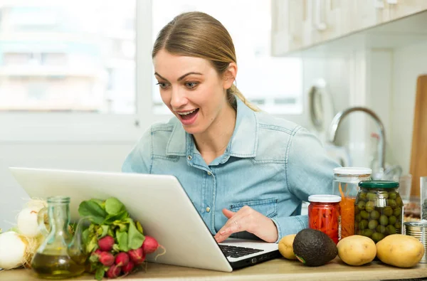 Ung kvinna matlagning recept från Internet — Stockfoto