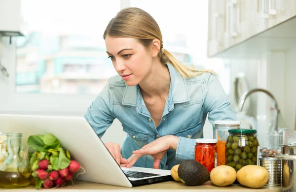 Ung kvinna matlagning recept från Internet — Stockfoto