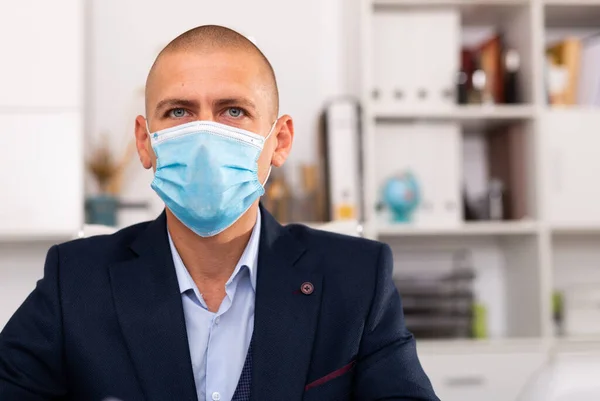 Berufskaufmann in medizinischer Schutzmaske mit Laptop am Arbeitsplatz — Stockfoto