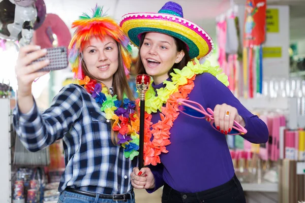 Chicas haciendo fotos divertidas selfies en la tienda de accesorios festivos —  Fotos de Stock