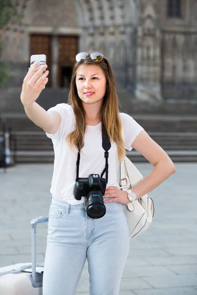 Leende kvinna med bagage gör selfie — Stockfoto