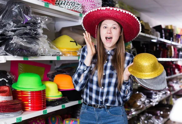 Chica buscando sombreros divertidos en la tienda —  Fotos de Stock